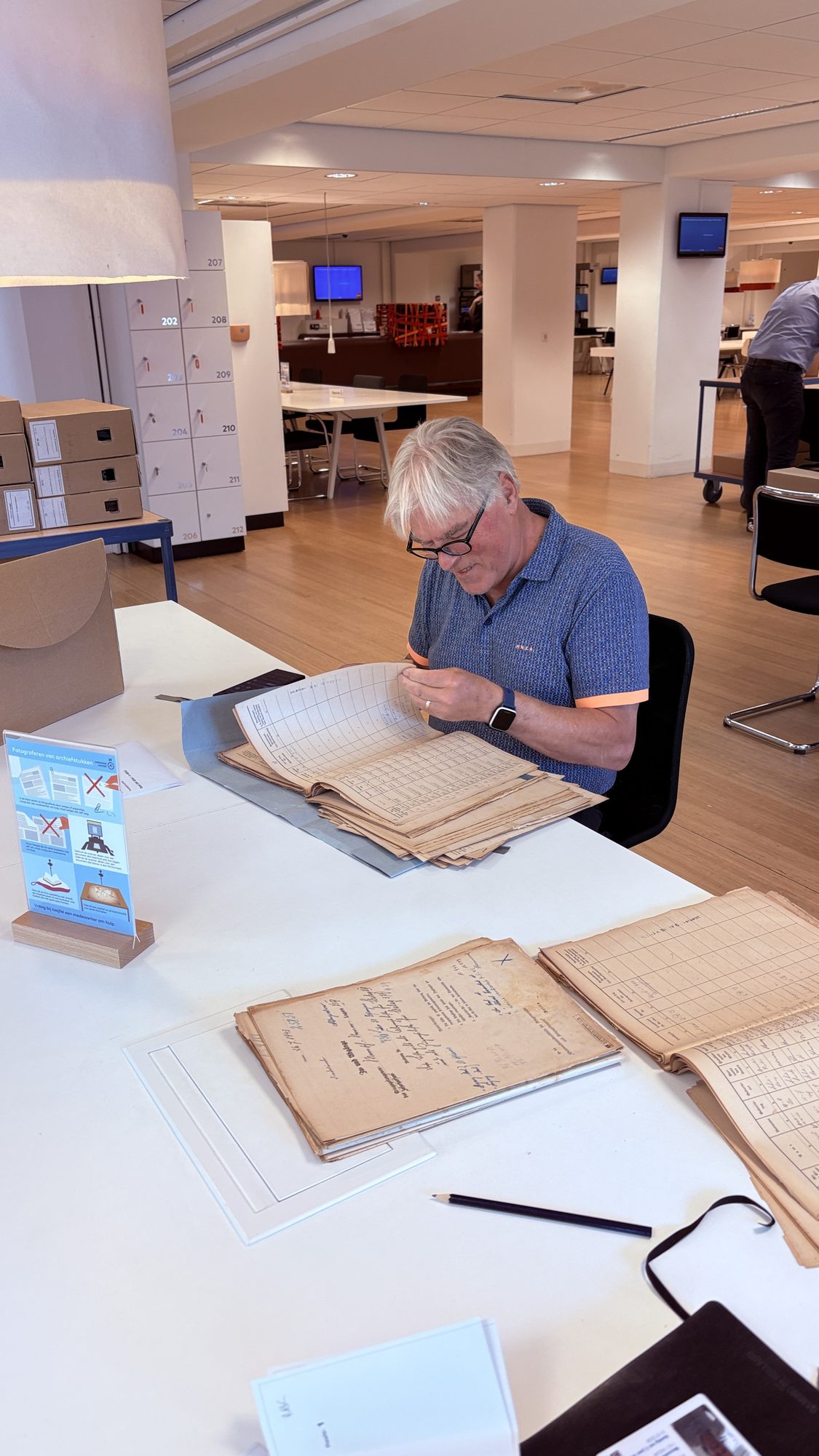 Ger Plaggenburg bladert door originele archiefregisters in de studiezaal van het Nationaal Archief.